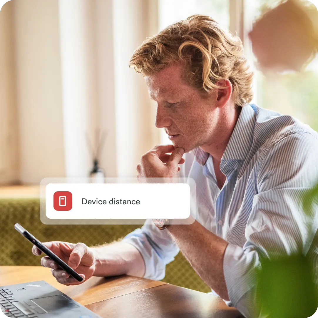 Man views smartphone and a 'Device distance' alert banner. Illustrates Duo's risk-based authentication, evaluating device proximity for security.