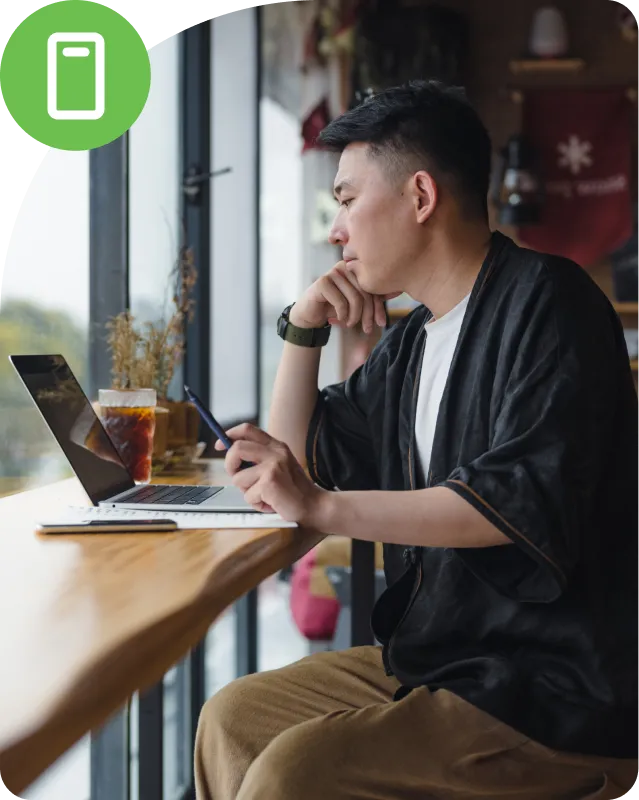 Person sitting on a table and checking the laptop to authenticate using dup mobile app